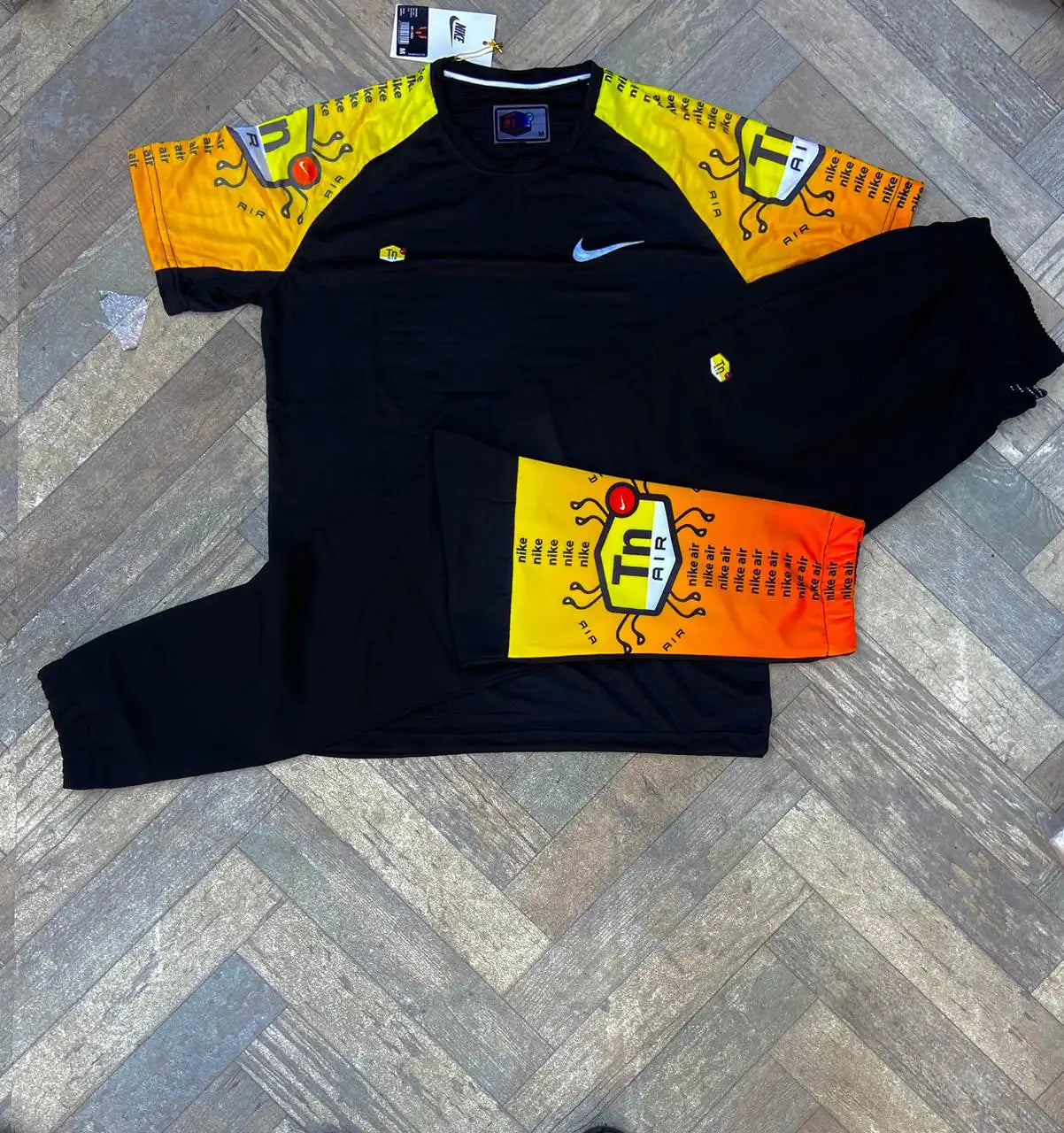 Conjunto NIKE TN negro logo plateado detales naranjas y amarillos