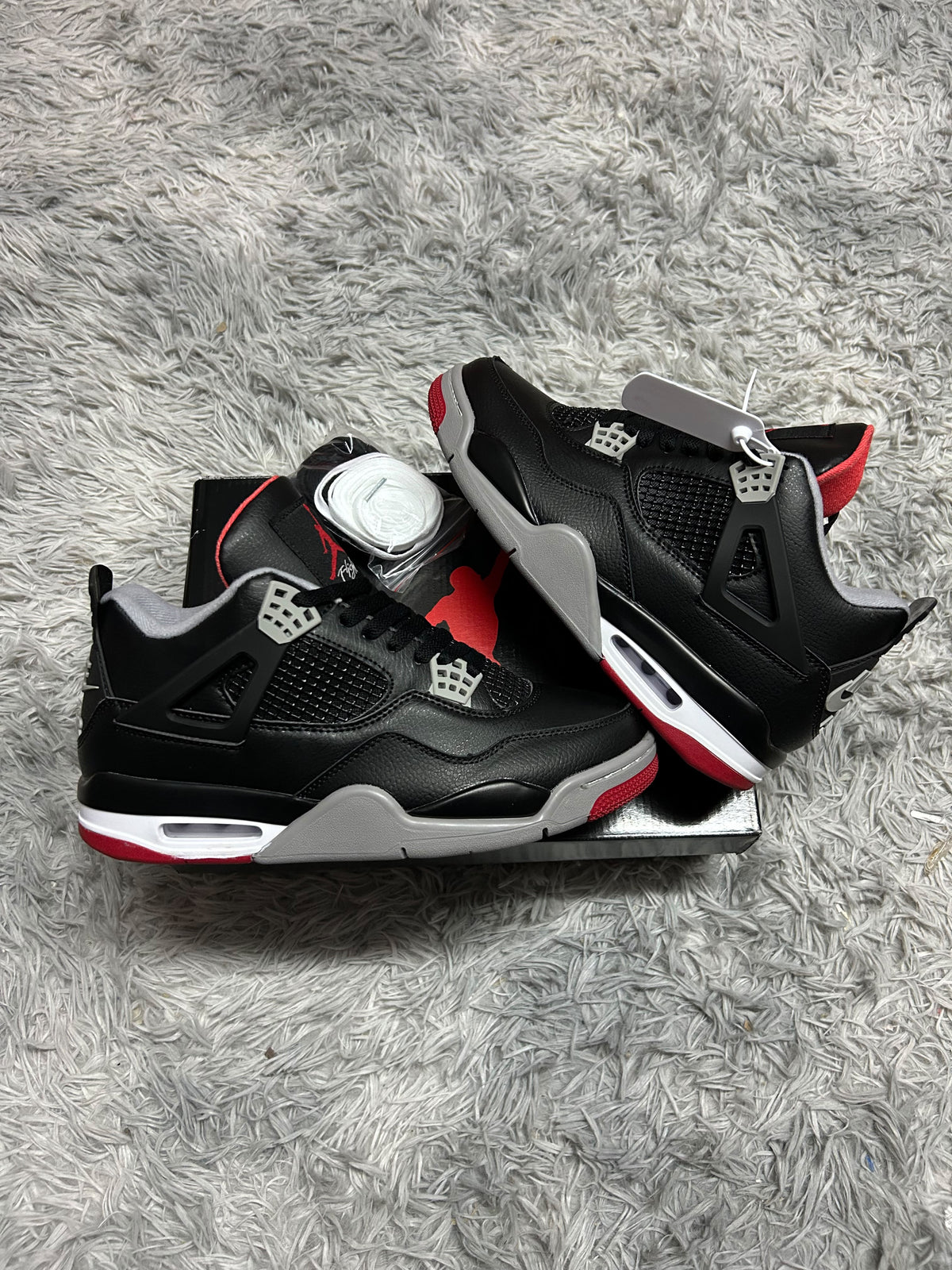 JORDAN 4 negras detalles blancos y grises rojas
